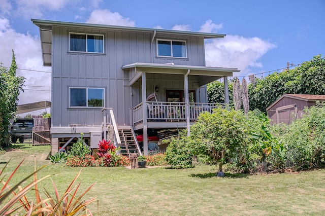 back of property featuring stairway, an outbuilding, a yard, and board and batten siding