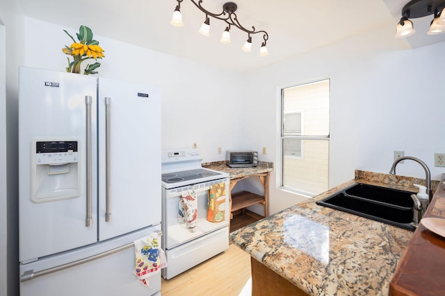 kitchen featuring a sink, light wood-style floors, and white appliances