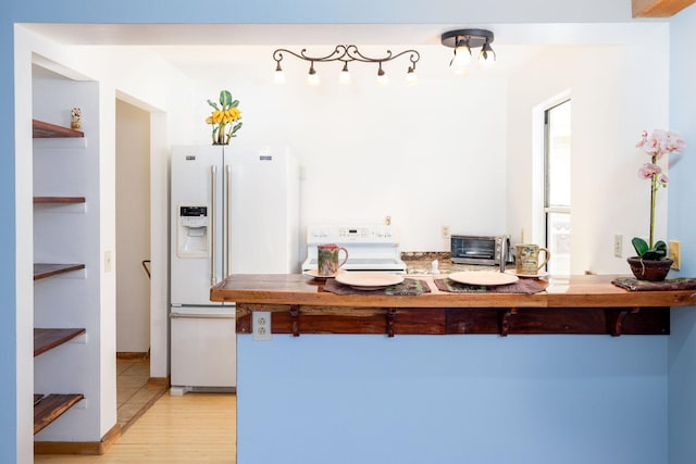 kitchen with light wood-style floors, a kitchen breakfast bar, stove, white fridge with ice dispenser, and a toaster