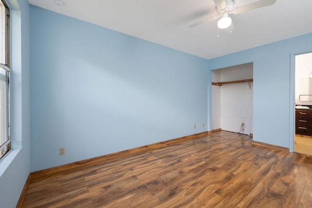 unfurnished bedroom featuring dark wood-style flooring, a ceiling fan, and a closet