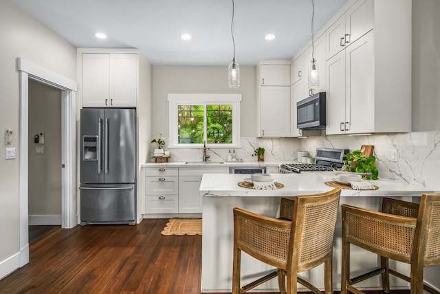 5413 Nakoa St, Koloa, HI 96756 - kitchen with stainless steel appliances, a sink, a peninsula, dark wood-style floors, and white cabinetry