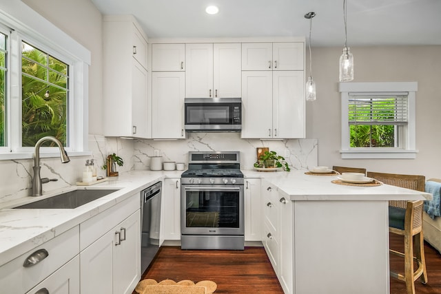 5413 Nakoa St, Koloa, HI 96756 - kitchen with appliances with stainless steel finishes, a sink, a peninsula, dark wood-style floors, and a kitchen bar