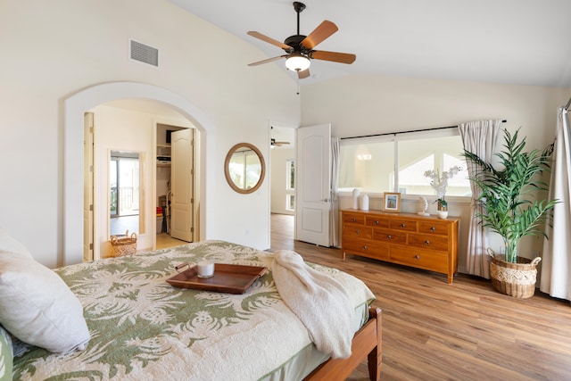 bedroom with arched walkways, light wood-style flooring, high vaulted ceiling, and a ceiling fan