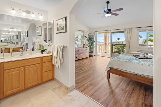 ensuite bathroom featuring a ceiling fan, vaulted ceiling, vanity, baseboards, and tile patterned flooring