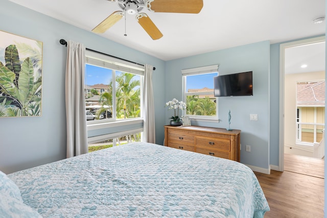bedroom featuring wood finished floors, baseboards, multiple windows, and a ceiling fan