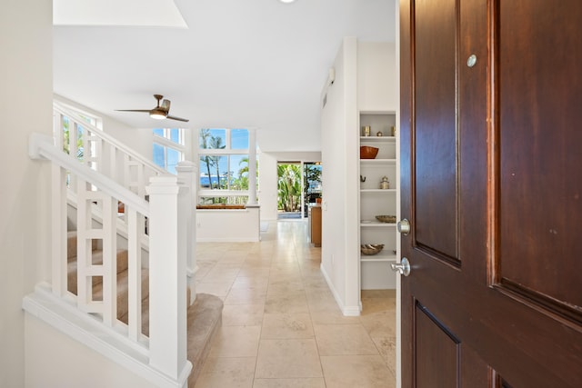 entrance foyer featuring a ceiling fan, stairs, light tile patterned flooring, and baseboards