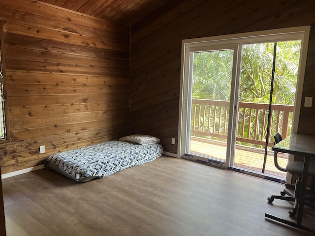 bedroom featuring access to exterior, wood walls, wood ceiling, and multiple windows