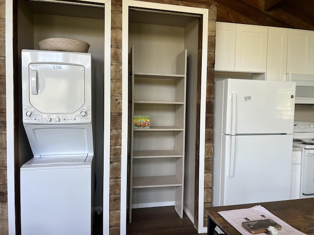 washroom with baseboards, dark wood-type flooring, stacked washer and clothes dryer, and laundry area