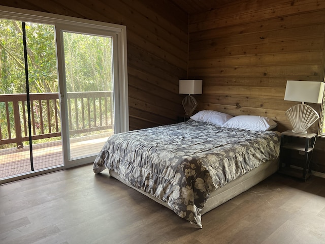 bedroom with wood finished floors, wood walls, and access to outside