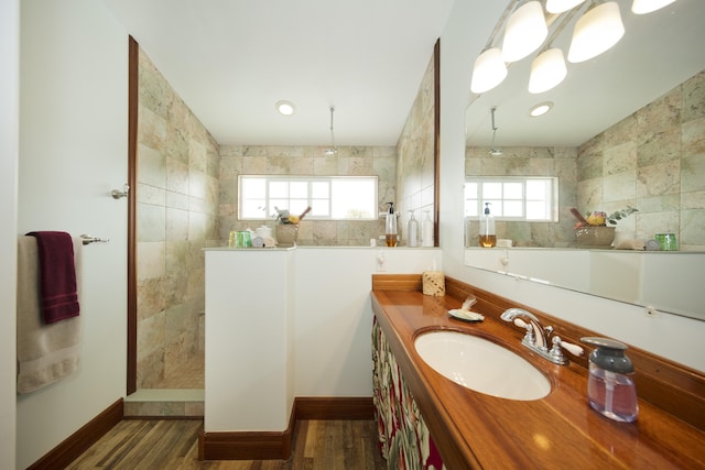 full bathroom with a walk in shower, baseboards, vanity, and wood finished floors