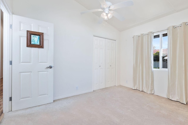 unfurnished bedroom with lofted ceiling, a closet, carpet, a ceiling fan, and baseboards