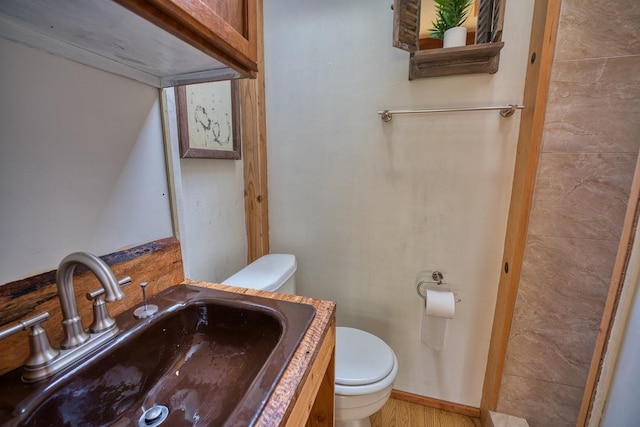half bathroom with toilet, vanity, and wood finished floors
