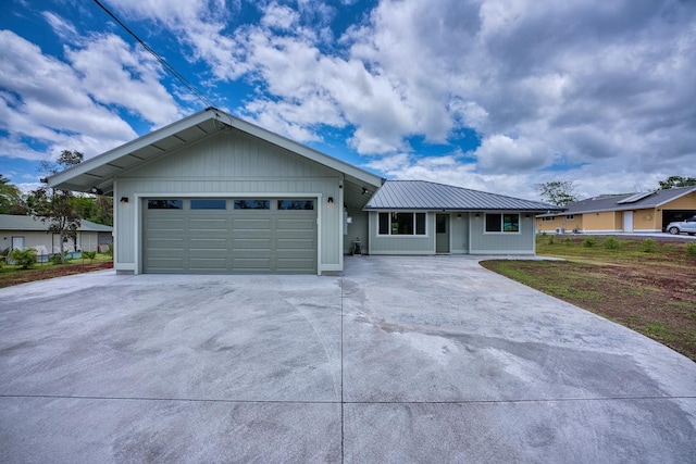ranch-style home with metal roof, concrete driveway, and a garage
