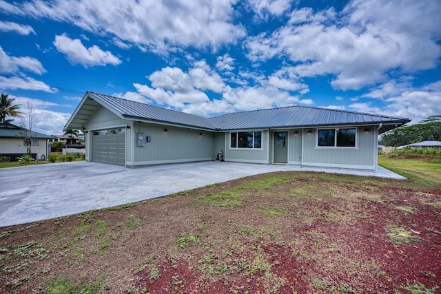 ranch-style home featuring metal roof, driveway, and an attached garage