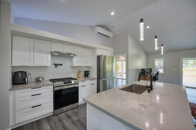 kitchen with a sink, stainless steel appliances, under cabinet range hood, an AC wall unit, and lofted ceiling