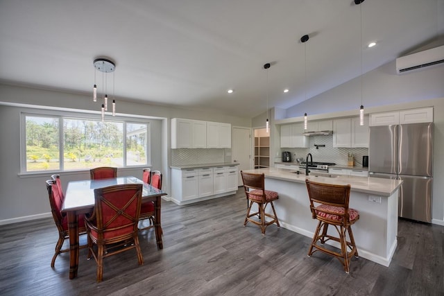 kitchen with tasteful backsplash, an AC wall unit, vaulted ceiling, and freestanding refrigerator