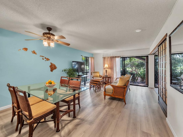 dining area with light wood-style floors, a wealth of natural light, and a textured ceiling