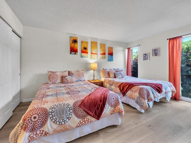 bedroom featuring wood finished floors, a textured ceiling, and access to exterior