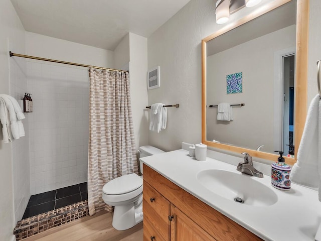 bathroom featuring tiled shower, wood finished floors, toilet, vanity, and visible vents