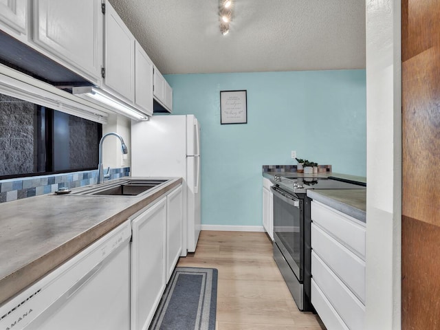 kitchen with a sink, white cabinets, light wood-style floors, and white appliances