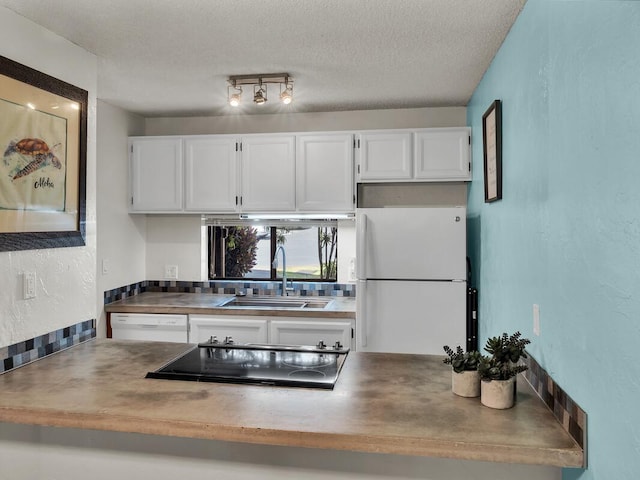 kitchen with a textured ceiling, white appliances, white cabinets, and a sink