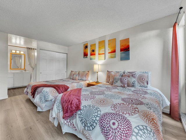bedroom featuring a textured ceiling, a closet, wood finished floors, and ensuite bath