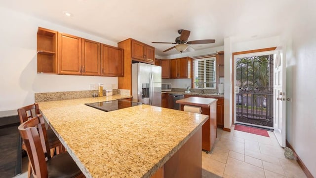 kitchen with appliances with stainless steel finishes, a peninsula, brown cabinets, a ceiling fan, and open shelves