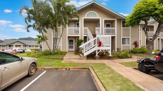 view of front facade with uncovered parking, stairway, and a front yard