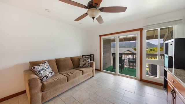 living area with ceiling fan and baseboards