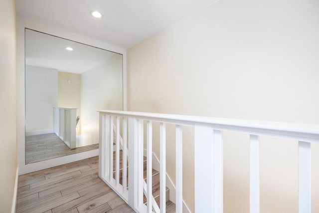 hall with recessed lighting, wood finished floors, and an upstairs landing