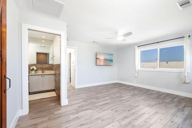 interior space featuring a ceiling fan, light wood-style flooring, and visible vents