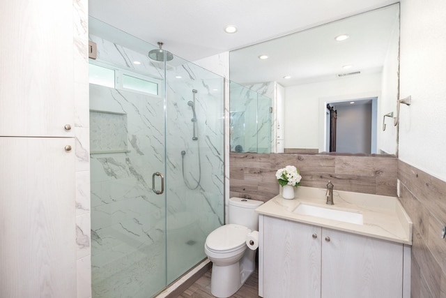 full bath featuring vanity, toilet, a marble finish shower, tile walls, and visible vents