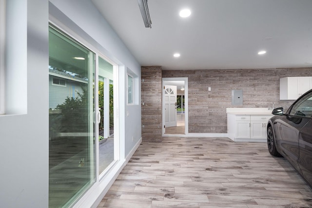 interior space featuring cabinet space, light wood-style floors, recessed lighting, baseboards, and electric panel