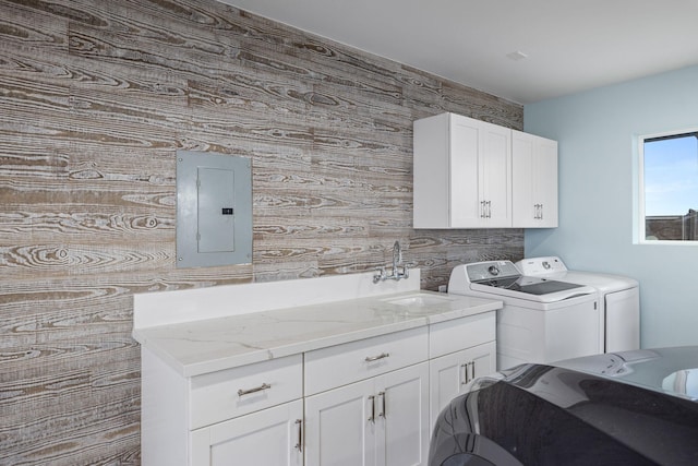 laundry area featuring a sink, electric panel, cabinet space, and washer and clothes dryer