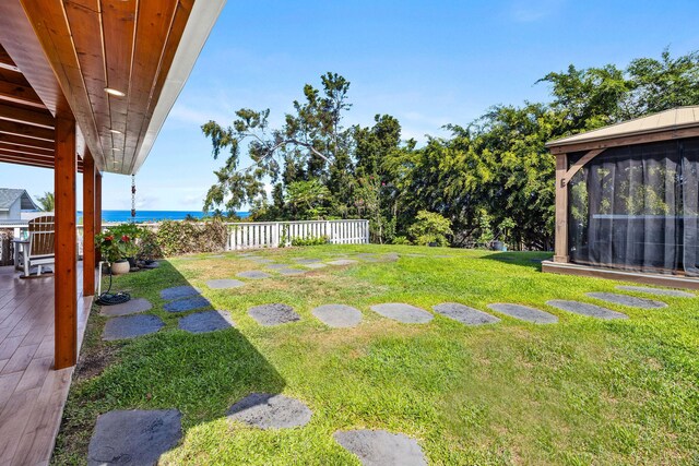 view of yard featuring a patio, a fenced backyard, a sunroom, and a water view