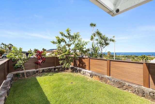 view of yard featuring a fenced backyard and a water view
