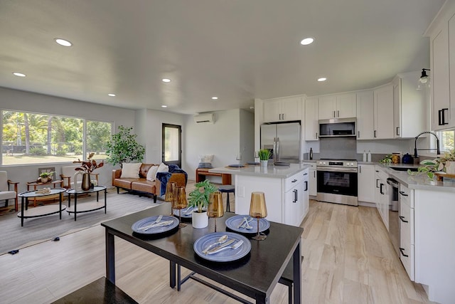 kitchen featuring plenty of natural light, appliances with stainless steel finishes, a wall mounted AC, and a sink