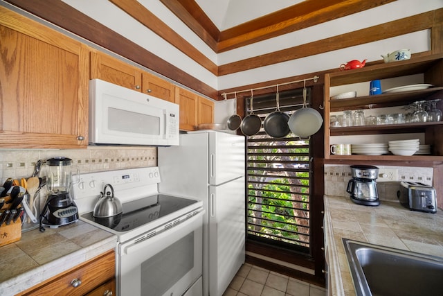 kitchen with white appliances, tile countertops, decorative backsplash, a sink, and light tile patterned floors