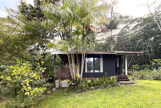 view of side of property with metal roof, a yard, and covered porch