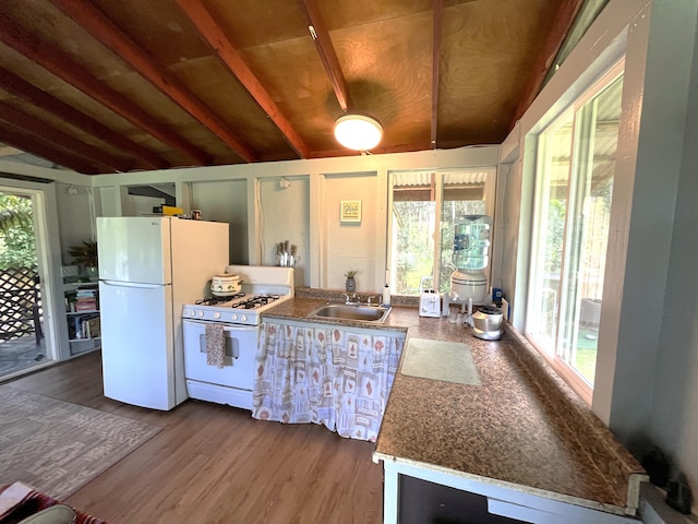 kitchen with white appliances, a sink, lofted ceiling with beams, and dark wood finished floors