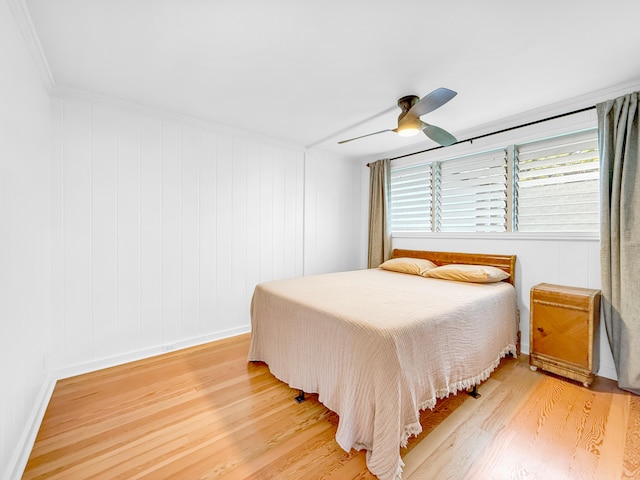bedroom with light wood-type flooring, ceiling fan, and ornamental molding