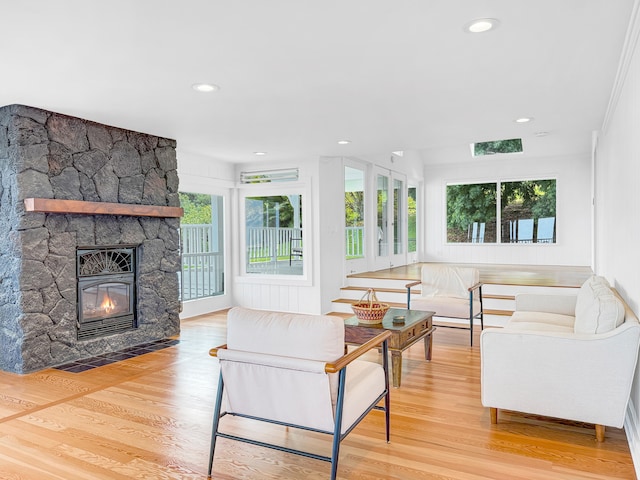 living room featuring wood finished floors, a stone fireplace, and recessed lighting
