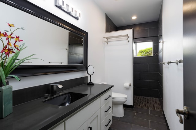 bathroom with toilet, recessed lighting, tile patterned floors, vanity, and tiled shower