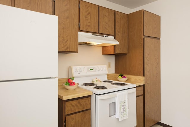 kitchen with white appliances, under cabinet range hood, light countertops, and brown cabinets