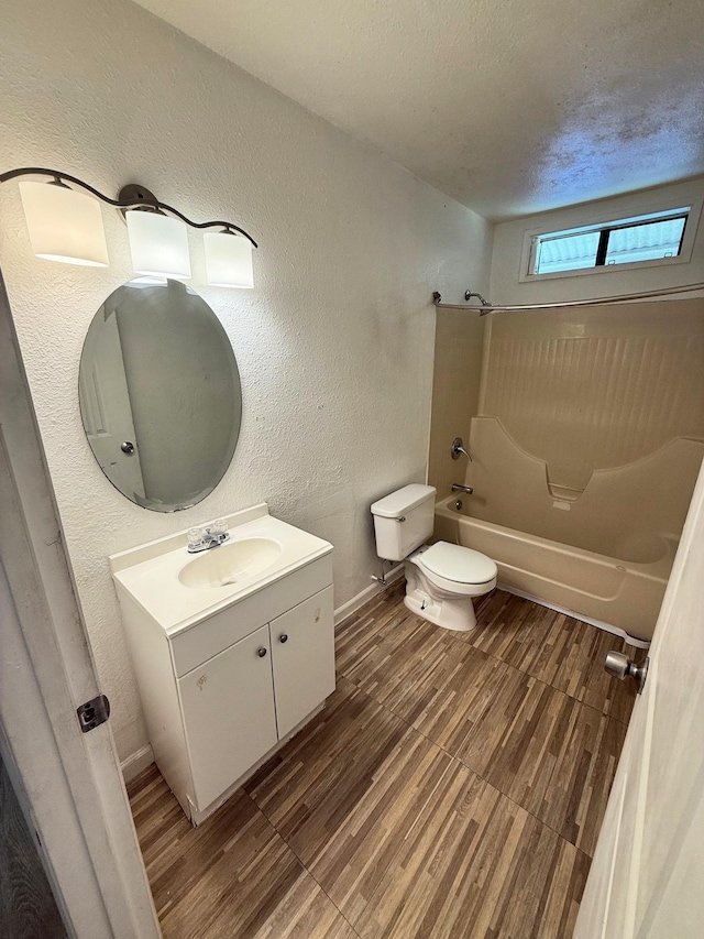 full bath featuring toilet, shower / washtub combination, wood finished floors, vanity, and baseboards
