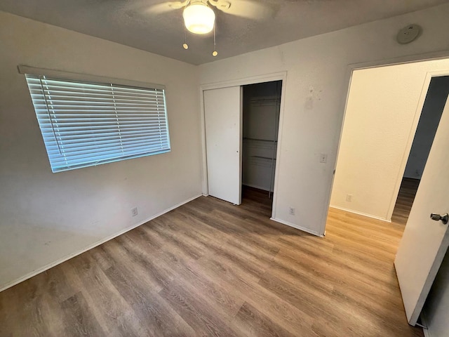 unfurnished bedroom featuring a closet, baseboards, a ceiling fan, and wood finished floors