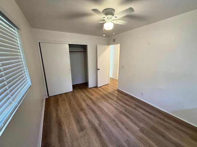 unfurnished bedroom featuring wood finished floors, a ceiling fan, a closet, a textured ceiling, and baseboards