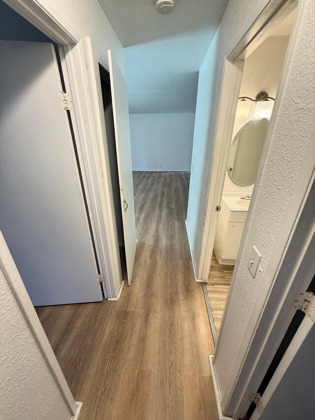 hallway featuring a textured wall and wood finished floors