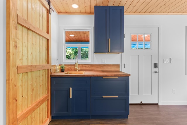 kitchen with butcher block countertops, wooden ceiling, a sink, blue cabinetry, and dark wood finished floors