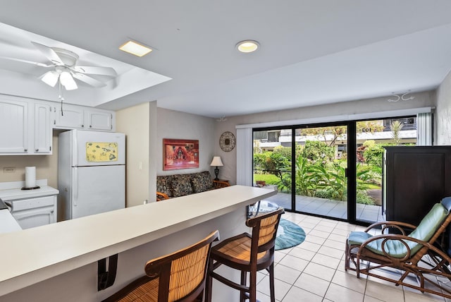 75-6082 Alii Dr Unit A103, Kailua-Kona, HI 96740 - kitchen featuring freestanding refrigerator, light tile patterned flooring, a breakfast bar, light countertops, and white cabinetry